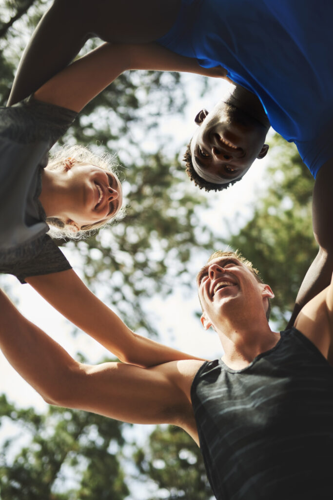 Fitness, happy or friends in nature for huddle for running exercise, training or outdoor workout together. People, low angle and healthy runners in park for motivation, support or sports teamwork.