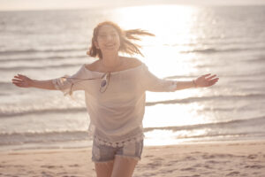 Freedom woman in free happiness bliss on beach, female model Smiling in summer enjoying serene ocean nature during travel holidays vacation outdoors.