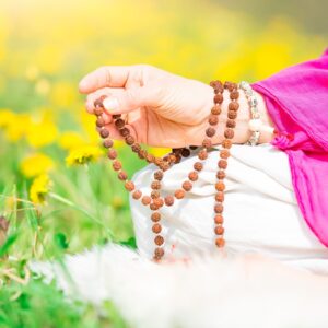 Mantra Meditation - picture of a person's hand, using a mala in meditation