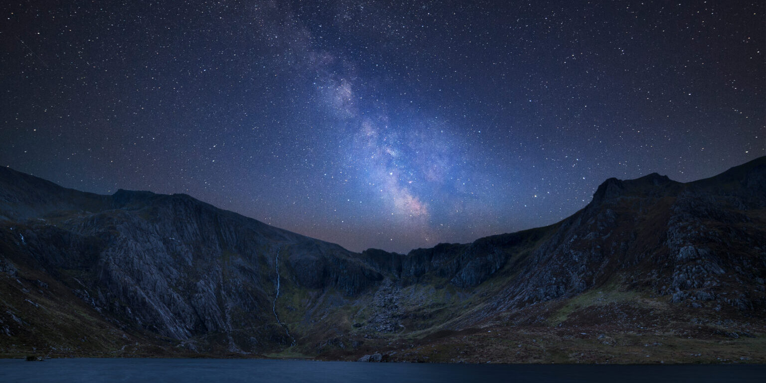 Stunning vibrant Milky Way composite image over Beautiful landscape image of Llyn Idwal and Devil's Kitchen in Snowdoina