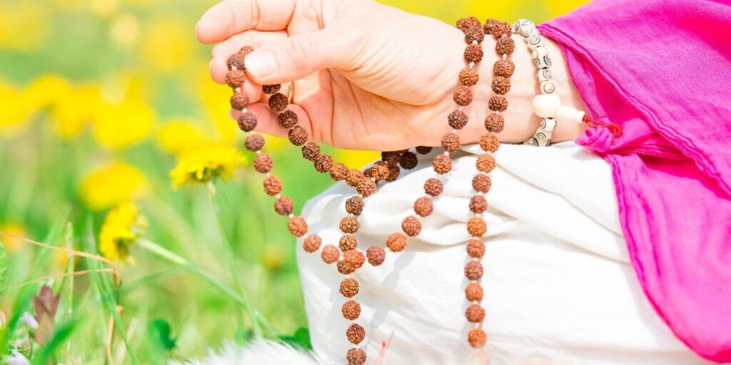 Mantra Meditation - picture of a person's hand, using a mala in meditation