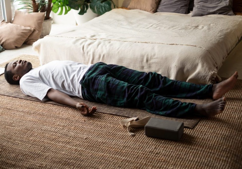 Young black man lying in Dead Body exercise or Corpse pose with his eyes closed, Savasana pose Young black man lying in Dead Body exercise or Corpse pose with his eyes closed, Savasana pose, working out, resting after practice